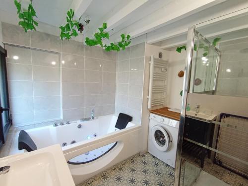 a bathroom with a tub and a washing machine at La Pépite du Sauternais in Preignac
