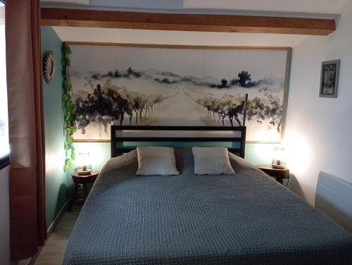 a bedroom with a bed with a painting on the wall at La Pépite du Sauternais in Preignac