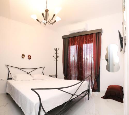a white bedroom with a bed and a chandelier at VenisHome 2 in Chrysoupolis