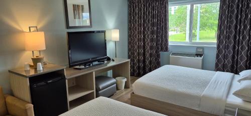 a hotel room with a bed and a flat screen tv at Mammas Inn in Niagara Falls