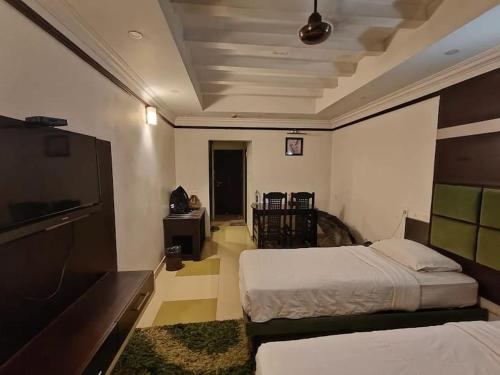 a bedroom with two beds and a flat screen tv at Continento the classic hotel in Malappuram