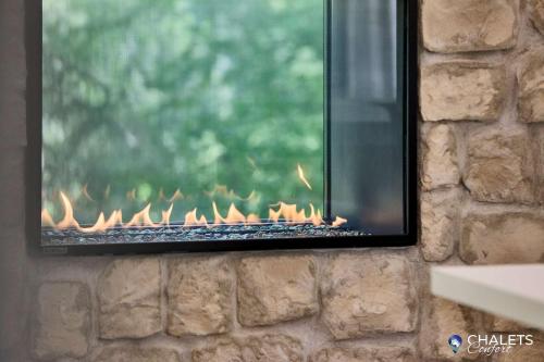 a fireplace on a stone wall with flames in it at Chalet Altitude Riverfront Pet-Friendly in Saint-Raymond