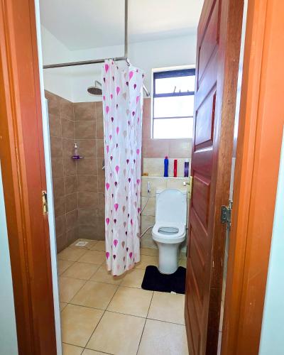 a bathroom with a toilet and a shower curtain at The Royals in Tatu City