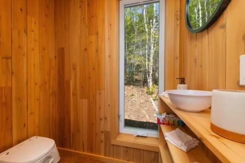 a bathroom with a toilet and a sink and a window at Tanières MicroChalets Charlevoix in Baie-Saint-Paul