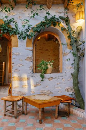 a stone building with a table and a tree at Berber Beldi Camp in Imsouane