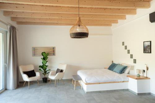 a bedroom with a bed and two chairs and a ceiling at Sage Suite in Paránimfoi