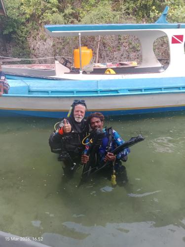 two men in the water in front of a boat at Lagoon Homestay in Keruo