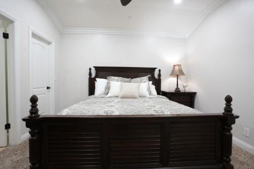 a bedroom with a large wooden bed with white pillows at Sweet 5 Bedroom, 4 Bath Pool Home 1/2 Mile Walk To Disney in Anaheim