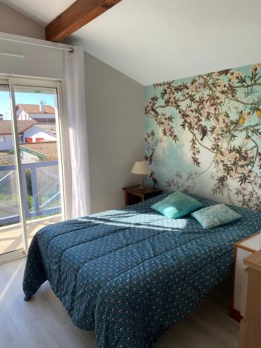 a bedroom with a bed with a tree mural on the wall at Agréable Maison basque-Anglet in Anglet