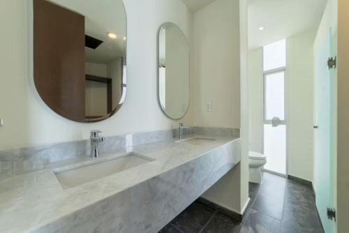 a bathroom with two sinks and a large mirror at Oceanfront Condo with Pool and Views Telchac | Depto B52 in Xtampú