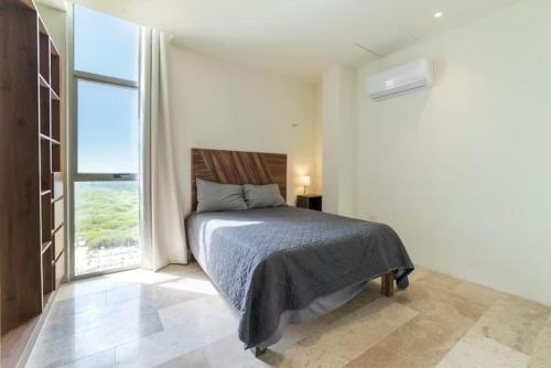 a bedroom with a bed and a large window at Oceanfront Condo with Pool and Views Telchac | Depto B52 in Xtampú