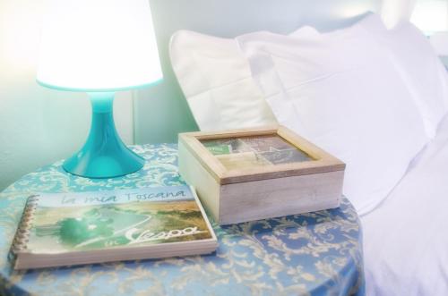 a table with a lamp and a book on a bed at Villa Gini in Pisa