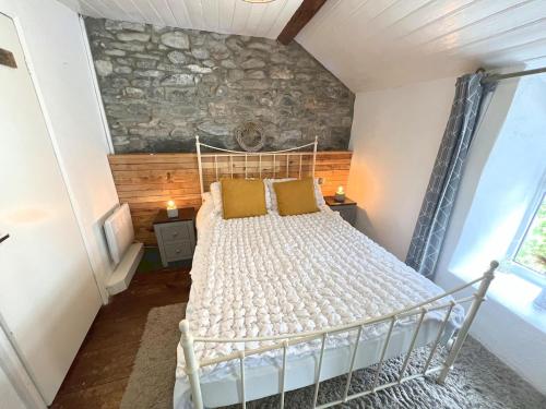 a bedroom with a white bed with a stone wall at Merrion Cottage Penmachno Betws y Coed Conwy in Penmachno