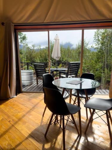 a patio with a table and chairs on a deck at Refugio Volcán Hornopiren in Hornopiren