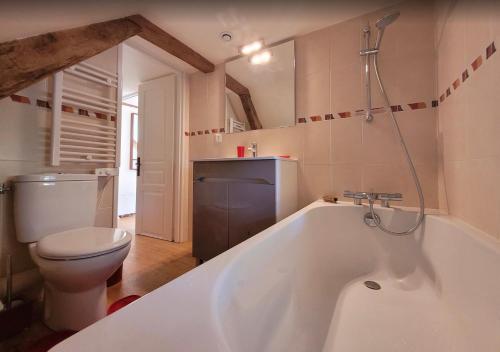 a bathroom with a white tub and a toilet at La Petite Ferme d'Autrefois in Saint-Georges-Nigremont