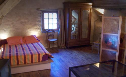 a bedroom with a bed and a table and a window at La Petite Ferme d'Autrefois in Saint-Georges-Nigremont
