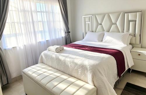 a bedroom with a white bed and a window at 2 Bed Cottage close to Westgate Shopping Centre in Harare