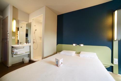 a bedroom with a white bed and a blue wall at Ibis Budget Chalon Sur Saone Nord in Chalon-sur-Saône