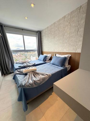 two beds in a room with a large window at Infinity 1206 - 2 Quartos a Passos da Praia com Garagem in Vila Velha