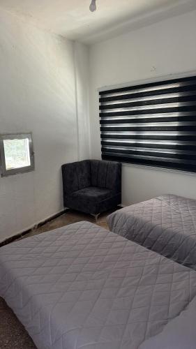 a bedroom with a bed and a chair and a window at Neue renovierte Wohnung mit Meerblick und große Balkon in tripoli ,Qalamoun in El Qalmoûn