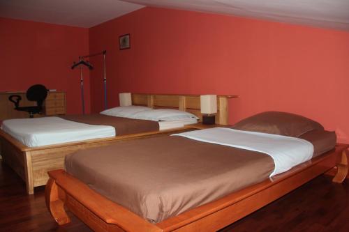 two beds in a room with red walls at LE Colibri in Le Dix-Septième