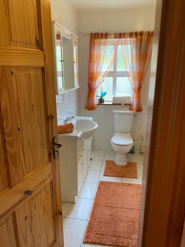 a bathroom with a toilet and a sink and a window at The Cliffs of Moher House, Doolin in Doolin