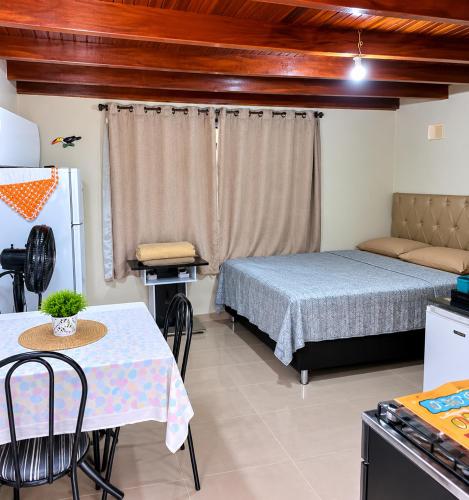 a room with two beds and a table and a refrigerator at Ouro Grosso Chales in Iporanga