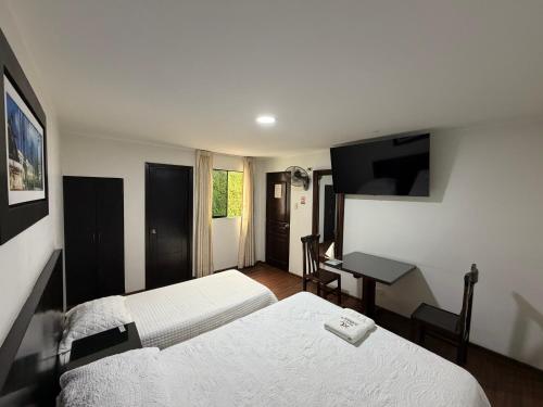 ein Hotelzimmer mit zwei Betten und einem Schreibtisch in der Unterkunft Hostal Anthony's in Lima