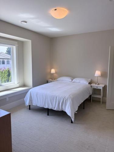 a white bedroom with a bed with two tables and a window at Mariposa Cozy Stay in Richmond