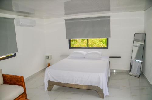 a white bedroom with a white bed and a window at Macao Sky pool suites in Punta Cana
