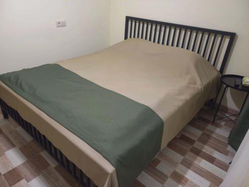 a bed with a green blanket on it in a room at Ani Center Hotel in Dovekh