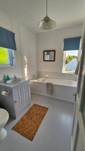 a white bathroom with a tub and a sink at The Ark Holiday Home in Stanford