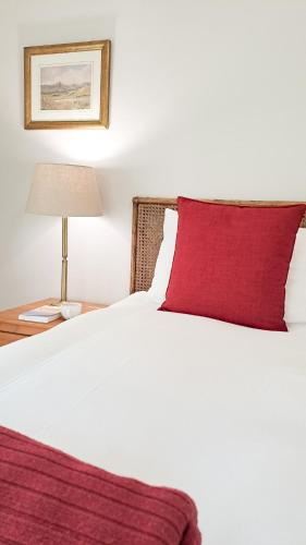 a bedroom with a white bed with a red pillow at Cruise Cottage in Stanford