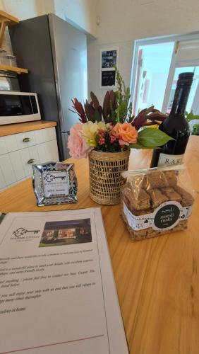 a table with a menu and flowers and a bottle of wine at Bramber cottage Stay a while in Stanford
