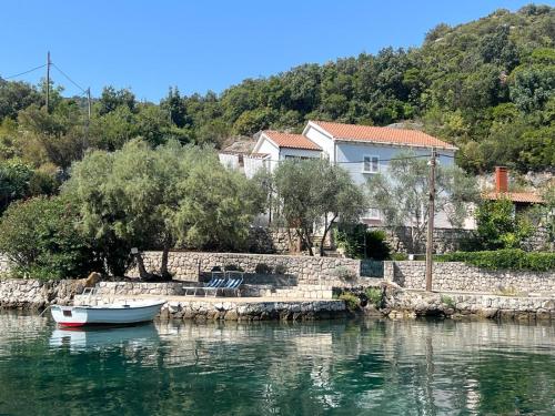 a boat in the water next to a house at Apartments Nadine Mljet Komfort mit Meerblick in Okuklje