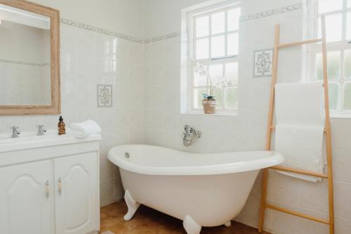 a white bathroom with a tub and a sink at Dove Cottage in Stanford