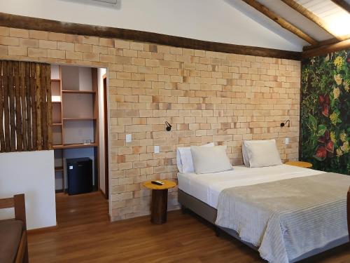 a bedroom with a bed and a brick wall at Vila Natholi Hotel Boutique in Imbassai