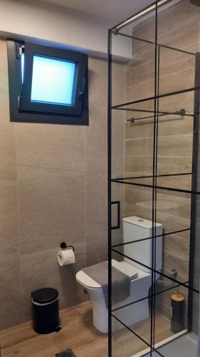 a bathroom with a toilet and a tv on a wall at Saos Terra Suites in Samothraki