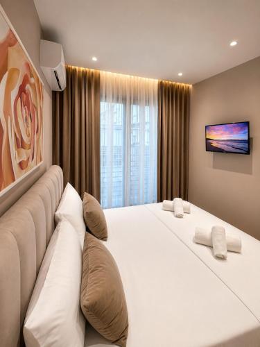 a bedroom with two large white beds and a tv at ODA Central Stay in Elbasan