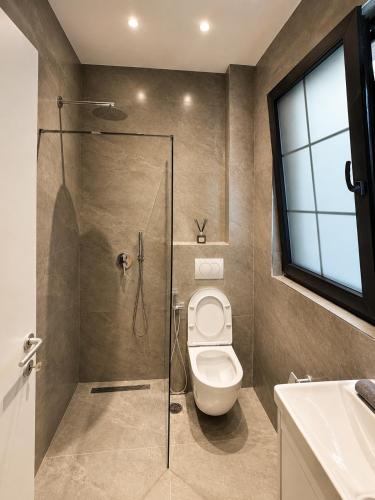 a bathroom with a toilet and a glass shower at ODA Central Stay in Elbasan