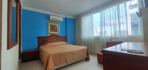 a bedroom with a bed and a blue wall at HOTEL VASCONIa in Cúcuta