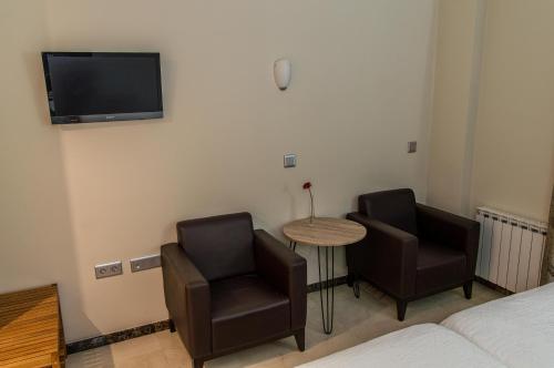 a bedroom with two chairs and a table and a tv at Hotel Sevilla in Ronda