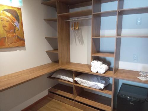 a walk in closet with wooden shelves and a tv at Vila Natholi Hotel Boutique in Imbassai