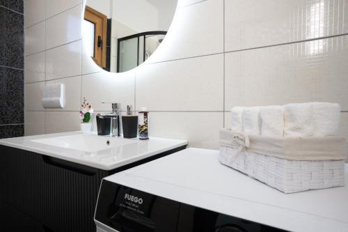 a white bathroom with a sink and a mirror at Oasis White in Durrës