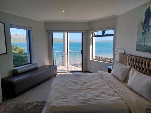 a bedroom with a bed and a view of the ocean at Sunset Villa in Langebaan