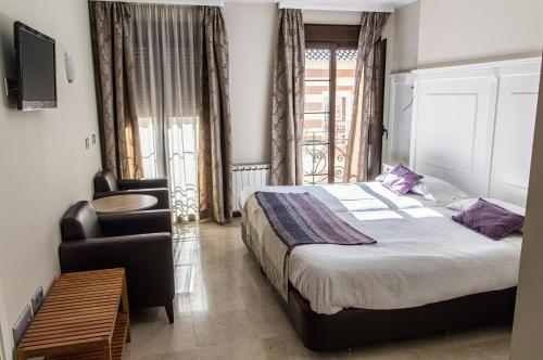 a bedroom with a bed and a chair and a television at Hotel Sevilla in Ronda