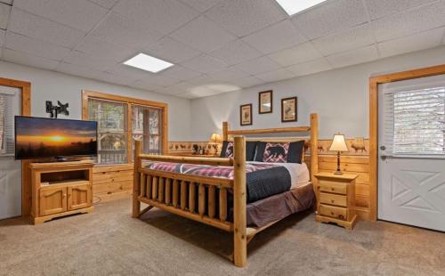 a bedroom with a bed and a flat screen tv at Bearadise Hot Tub 6 Min to The Island in Pigeon Forge