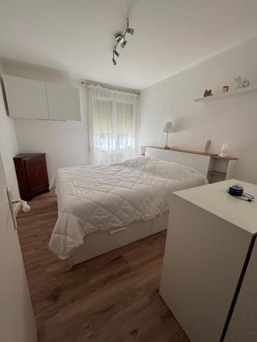 a white bedroom with a bed and a table at Appartement Montalieu in Montalieu-Vercieu