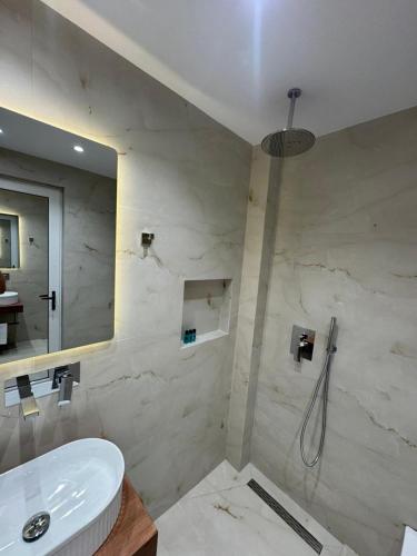 a bathroom with a sink and a shower with a mirror at Hotel Barjami in Sarandë