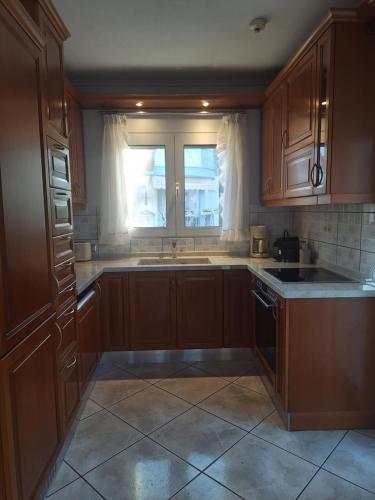 a kitchen with wooden cabinets and a sink and a window at SeafrontGardenHouse Villa in Iraklitsa